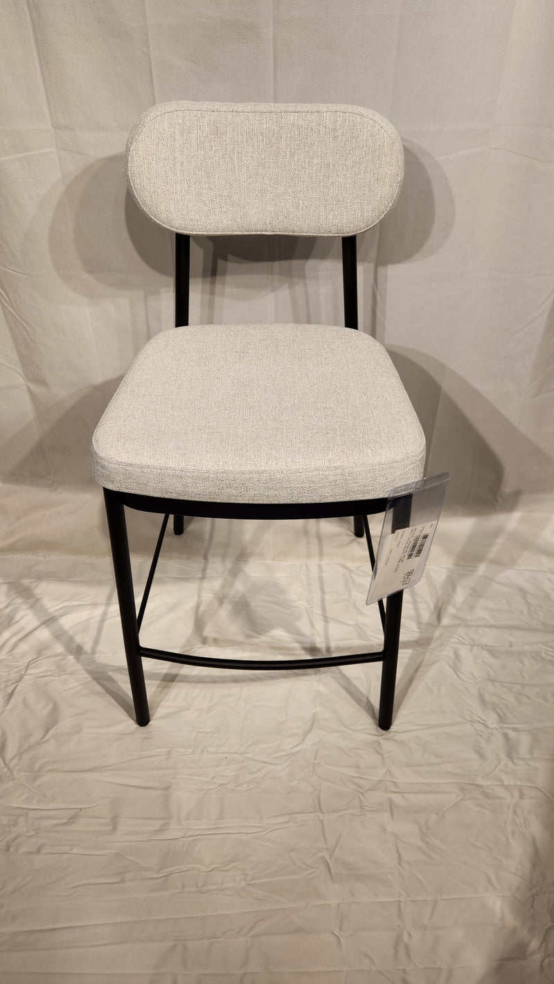 The Amisco Orly Counter Height Bar Stool features a light gray cushioned seat, backrest, and black metal legs on white.