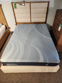 A neatly made bed with a Tempur-pedic Pro Align 2.0 - Firm mattress and padded headboard, set among wooden furniture.