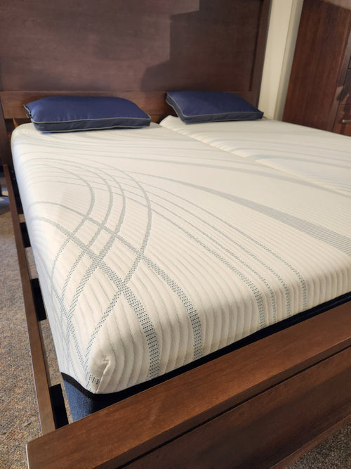 A wooden bed frame with navy pillows and a Tempur-pedic Align - Firm mattress for body-conforming support.