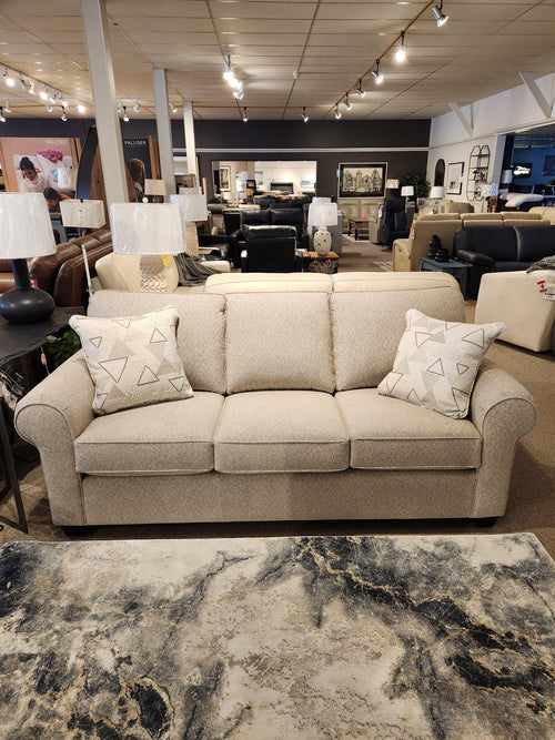 In a showroom, the Decor-rest 2179 Sofa in beige features stylish upholstery and patterned pillows among home decor items.