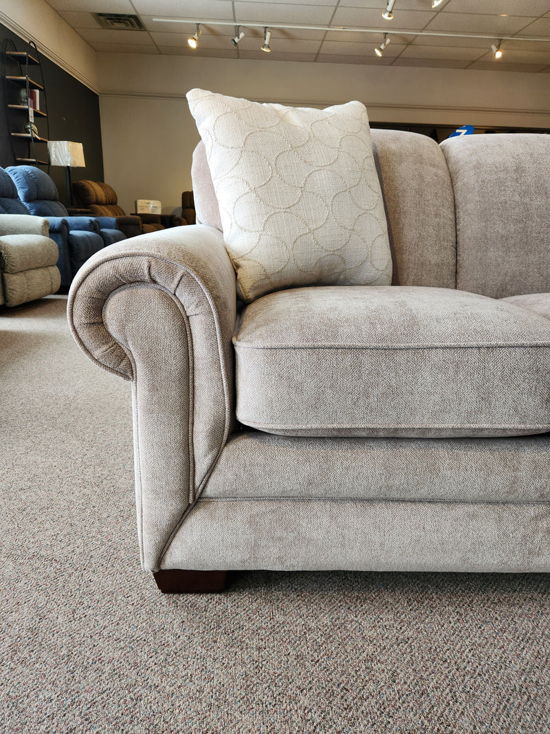 Close-up of a La-Z-Boy 435 Mackenzie Queen Sofa Bed with ComfortCore® cushions and rolled arms on a carpeted showroom floor.