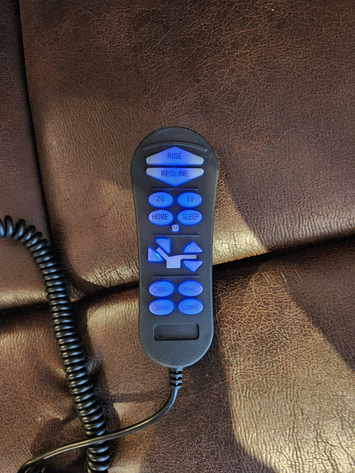 A Rhodes PL442L power lift chair remote with blue backlit buttons rests on brown leather to control 4-Zone features.