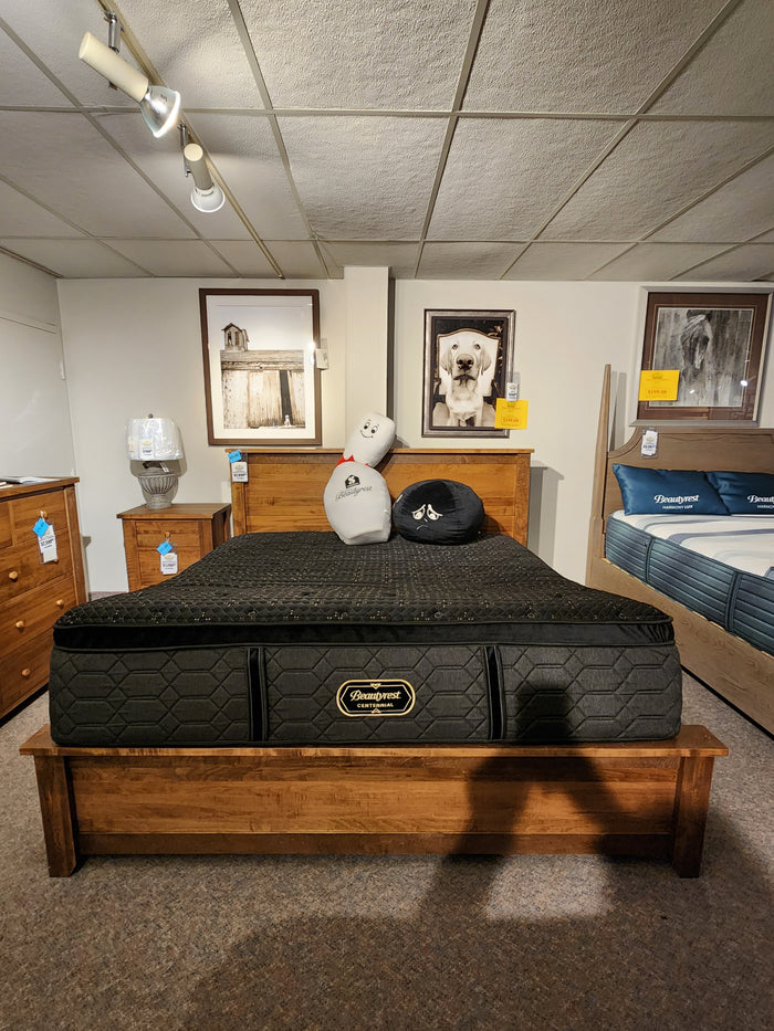 A Beauty-rest Hermes Ultra Plush Mattress on a wooden frame, with pillows and animal photos in the showroom.