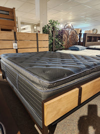 A Beauty-rest Lusso Plush SPT Mattress with a cool surface rests on a wooden bed frame in a showroom.