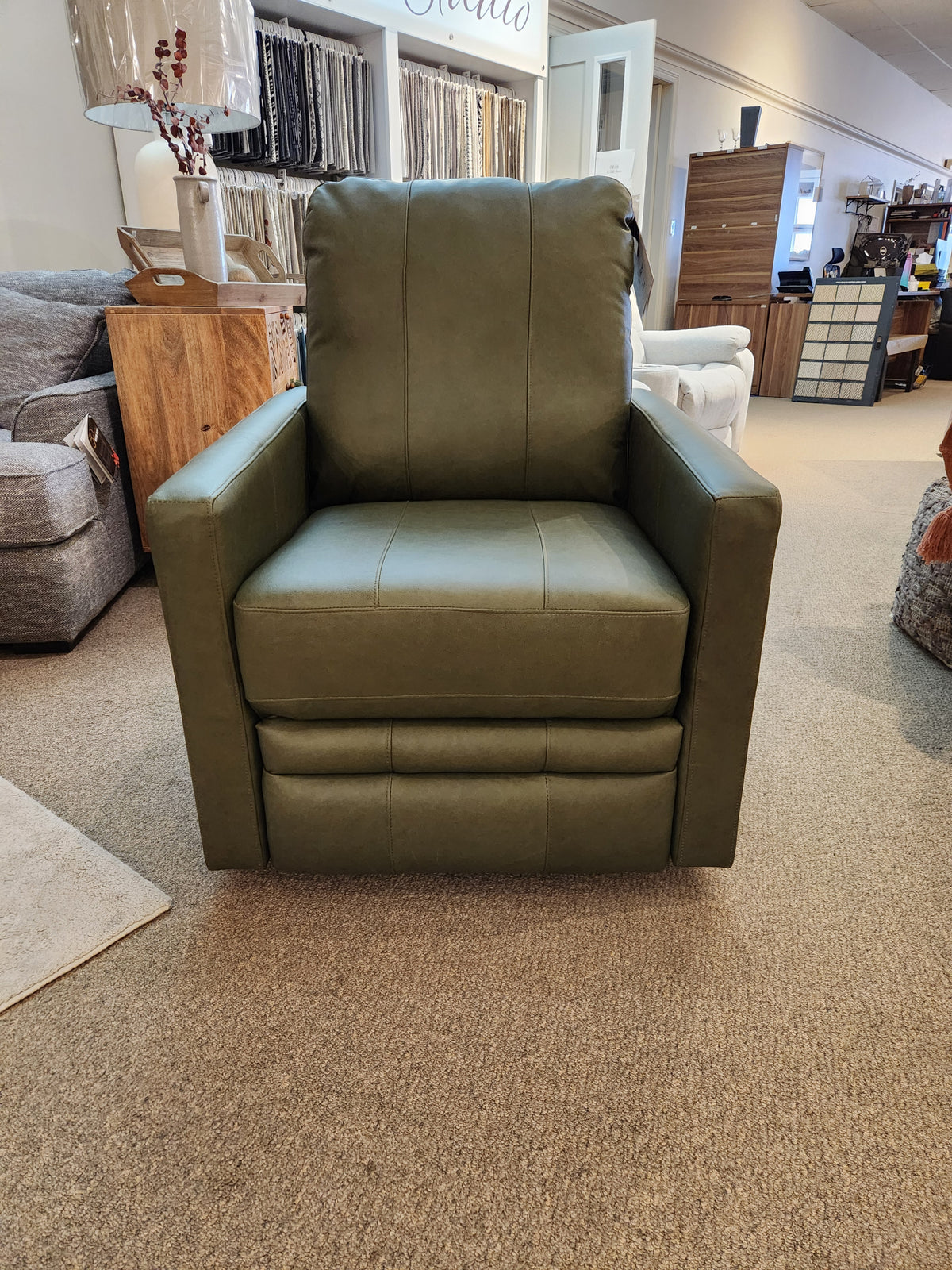 The Best Kristisha Swivel Push-back Recliner in green features a modern silhouette among other furnishings.