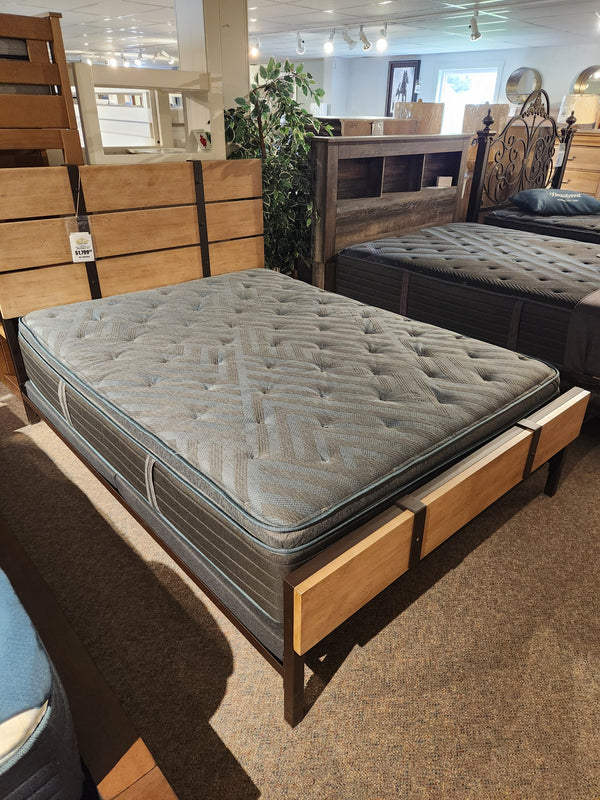 A Beauty-rest Eryx PT Medium Mattress is displayed on a wooden bed frame in a showroom.