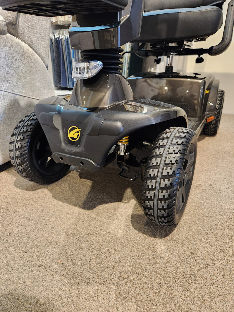 Close-up of the front wheels and base of the Golden Companion Full-Size Mobility Scooter on a carpeted floor.