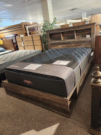 A queen bed with storage, headboard shelf, and Beauty-rest ESME TT Medium Mattress is on display in the showroom.