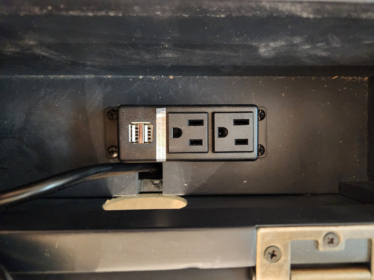 The Jofran Craftsman Power Chairside Table features a black outlet with two sockets and USB ports in a dark compartment.