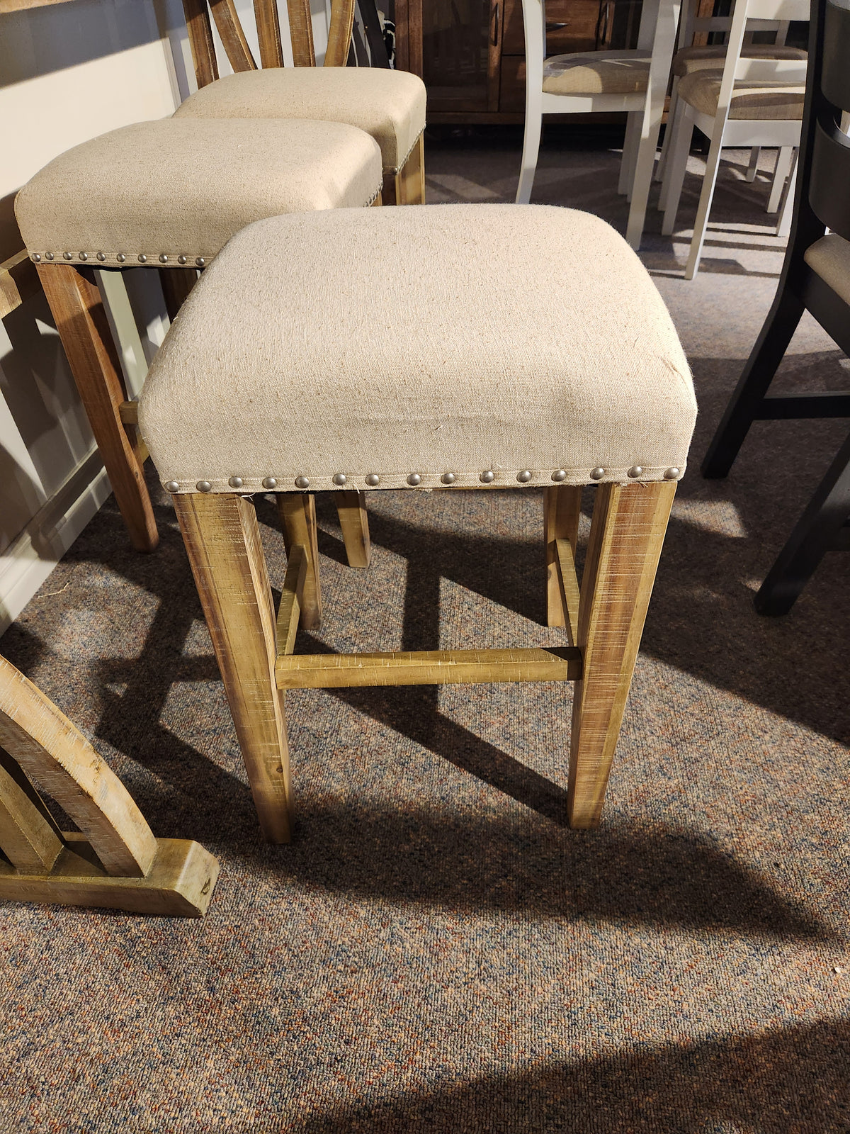The Jofran 1933-74 Fairview Counter Table with 3 Stools features linen-blend upholstery and metal stud accents.