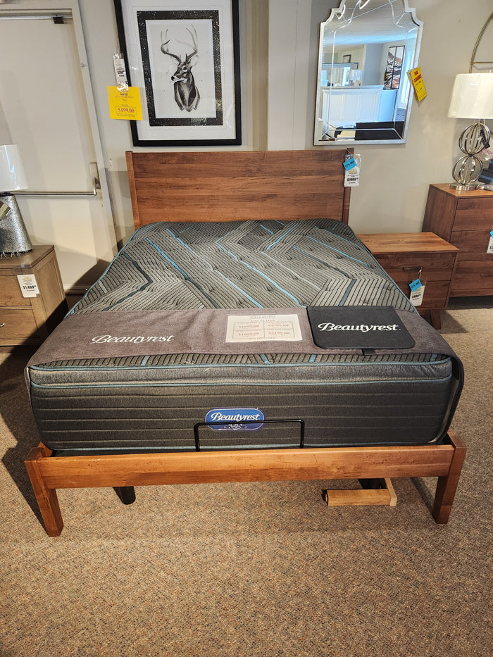 A Beauty-rest Echo PT Medium Mattress on a wooden frame in a stylish showroom.