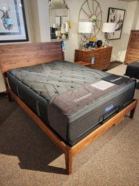 A Beauty-rest Echo PT Medium Mattress by Beauty-rest on a wooden bed frame in a stylish showroom.
