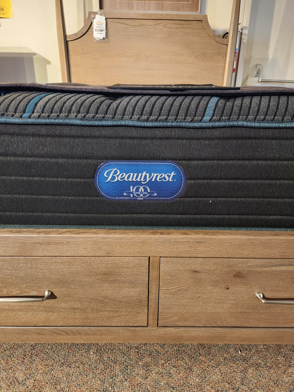A Beauty-rest Mira TT Medium Mattress rests on a wooden drawer platform in the showroom.