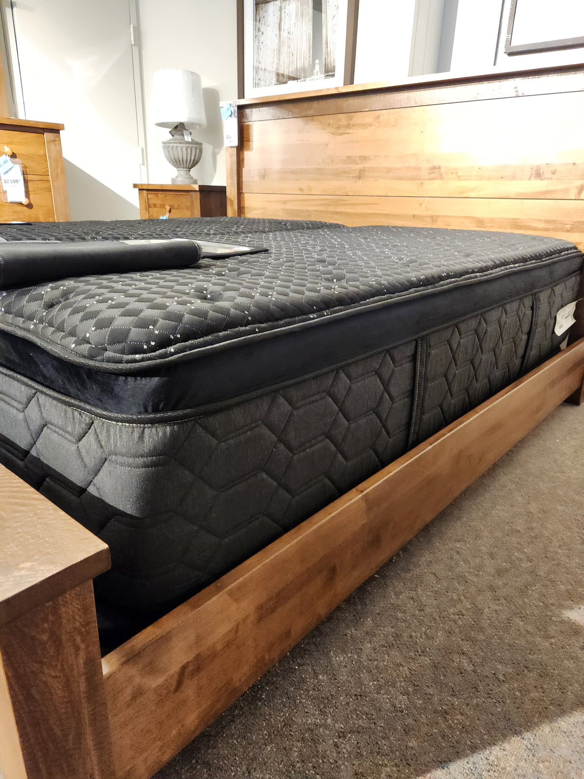 The Beauty-rest Apollo PT Medium Mattress with a pocket coil system is displayed on a wooden bed in the showroom.
