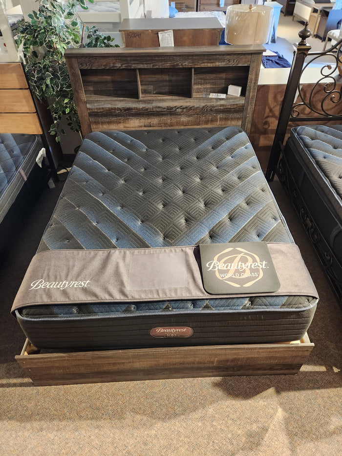A Beauty-rest Haven TT Firm Mattress on a wooden bed frame in a brightly lit showroom.