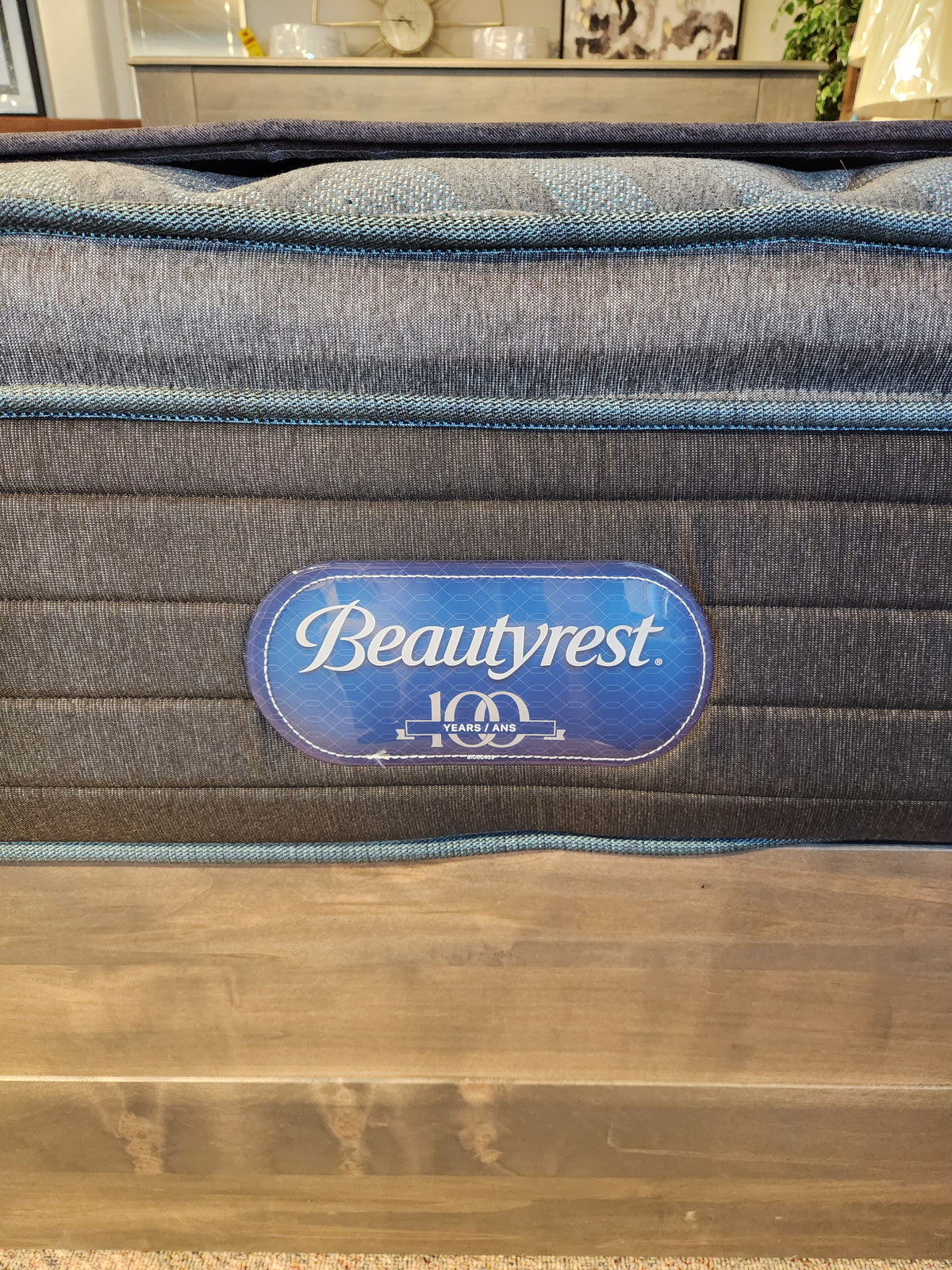 Close-up of Beauty-rest Isla PT Firm Mattress tag with "100 years" logo on quilted fabric, featuring Pocket Coil Tech.