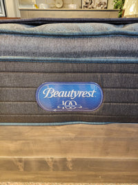 Close-up of Beauty-rest Isla PT Firm Mattress tag with "100 years" logo on quilted fabric, featuring Pocket Coil Tech.