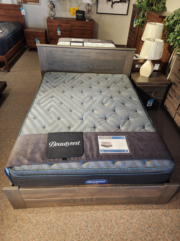 A Beauty-rest Isla PT Firm Mattress by Beauty-rest with pocket coils on a wooden frame, displayed with nightstands.