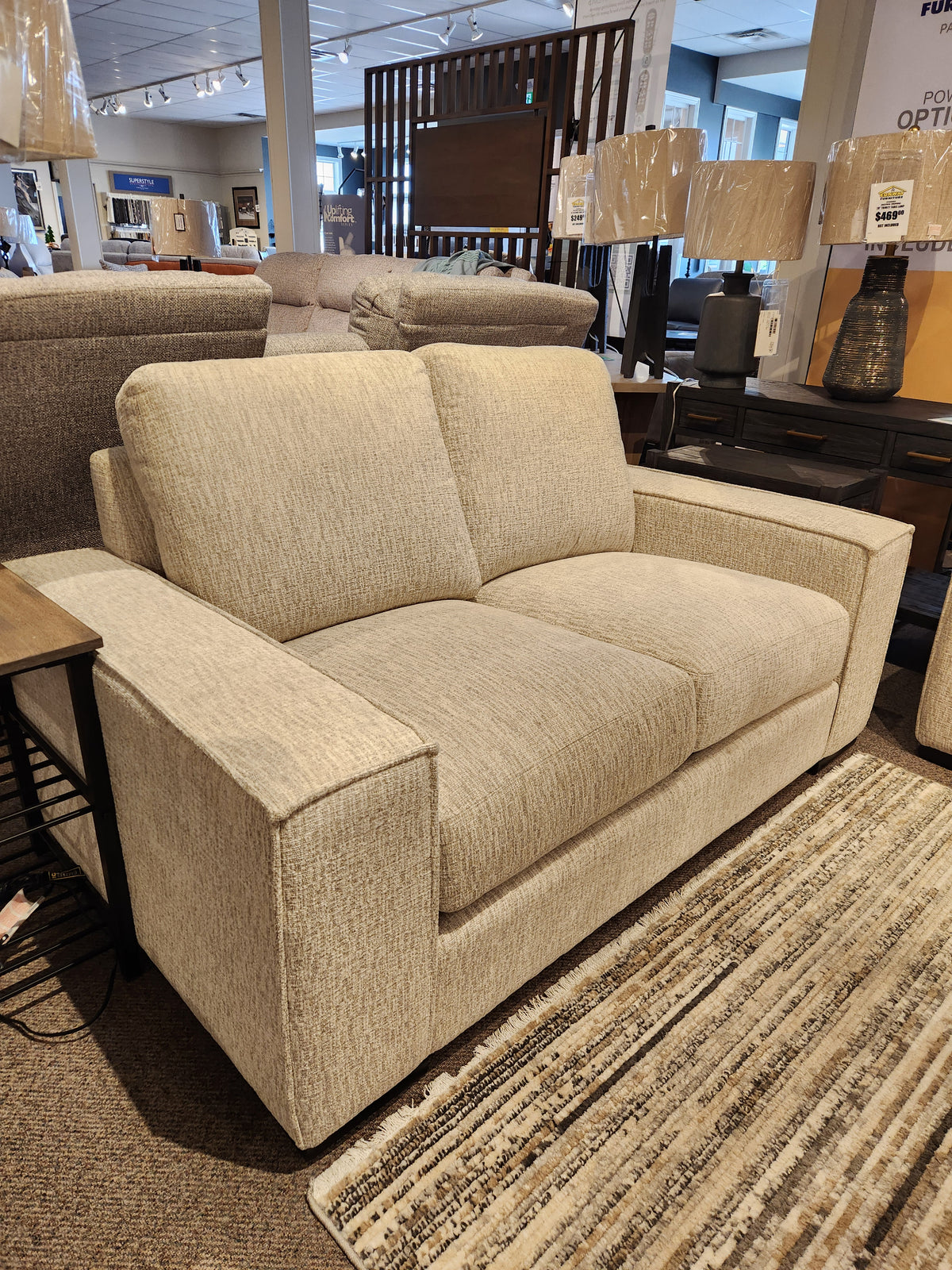 The Leather Craft Mesa Loveseat exudes modern comfort, beautifully paired with a rug and side table in the showroom.