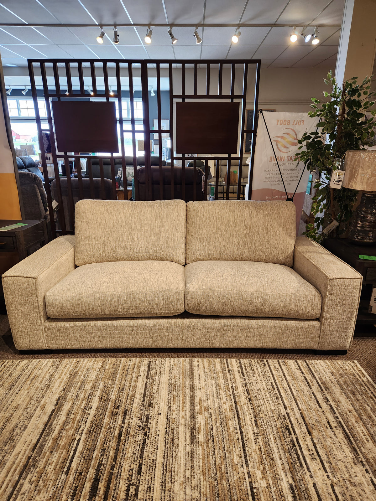 The Leather Craft Mesa Sofa offers luxurious comfort with square arms, displayed in a showroom with a striped rug.