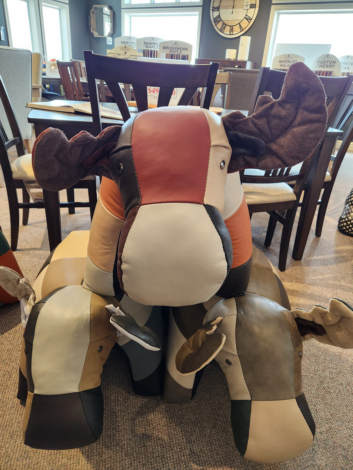 Three Reiner's Originals Moose Leather Animal Ottomans are displayed on a carpeted showroom floor.