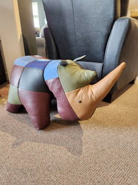 Reiner's Originals Reiner's Leather Animal Ottomans-- Rhino sits on the carpet in front of a black armchair.