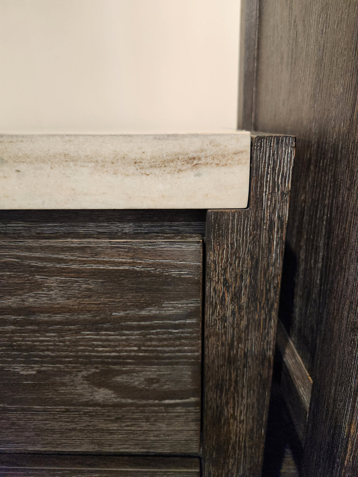 Close-up of the Magnussen B5990 Plum Creek Night Stand in Ravenwood Black with beige stone top, showing corner detail.
