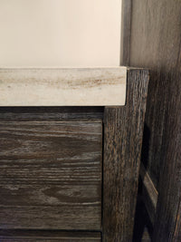 Close-up of the Magnussen B5990 Plum Creek Night Stand in Ravenwood Black with beige stone top, showing corner detail.