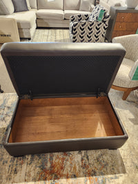 Superstyle 5000-57 Superstyle Storage Ottoman with hinged lid and storage, shown open on a rug in a store.