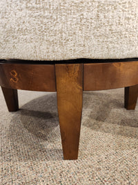 Close-up of the wooden legs and lower frame of a Best Attica Swivel Chair on a speckled carpeted floor.
