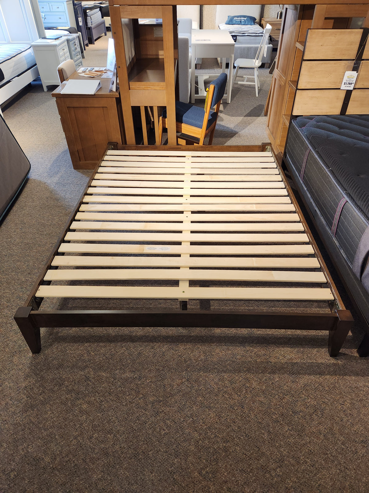 The Fashion Willa Queen Platform Bedframe with minimalist design is displayed in a furniture showroom.