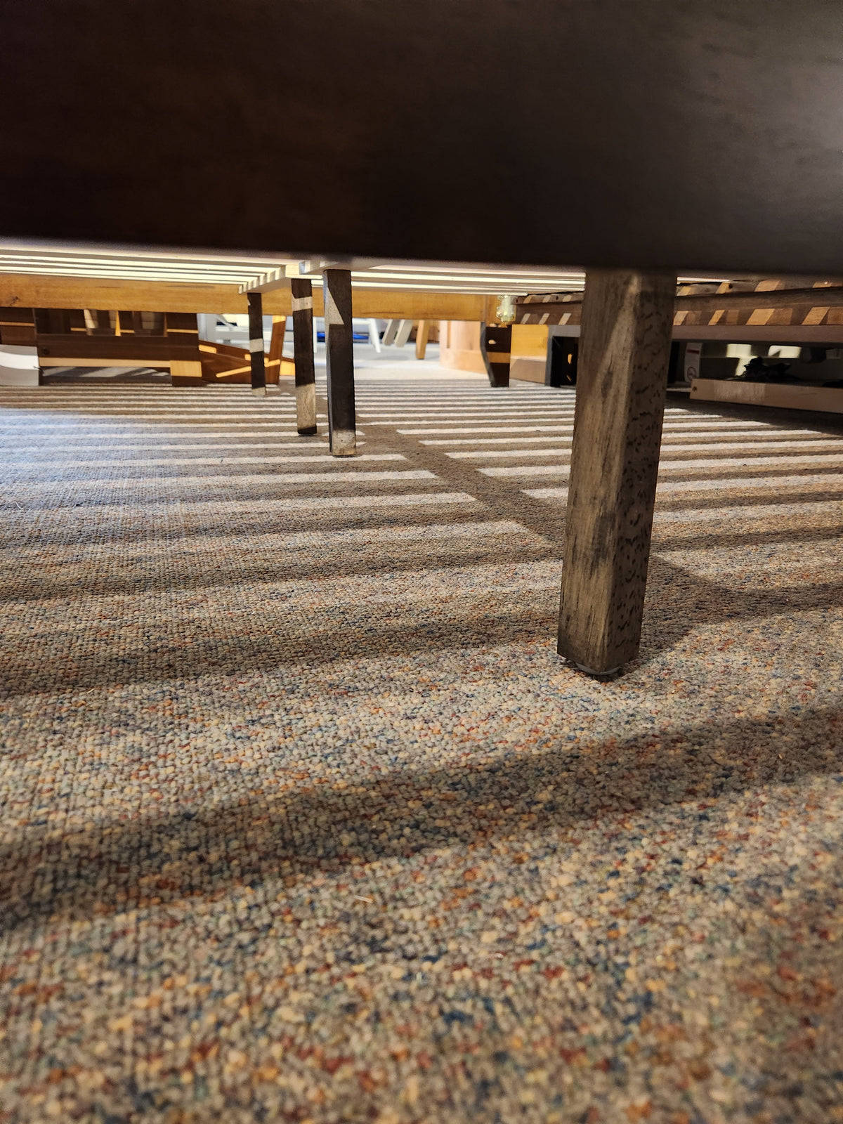 Low angle view under a Fashion Willa Queen Platform Bedframe with metal legs, highlighting its minimalist look on carpet.