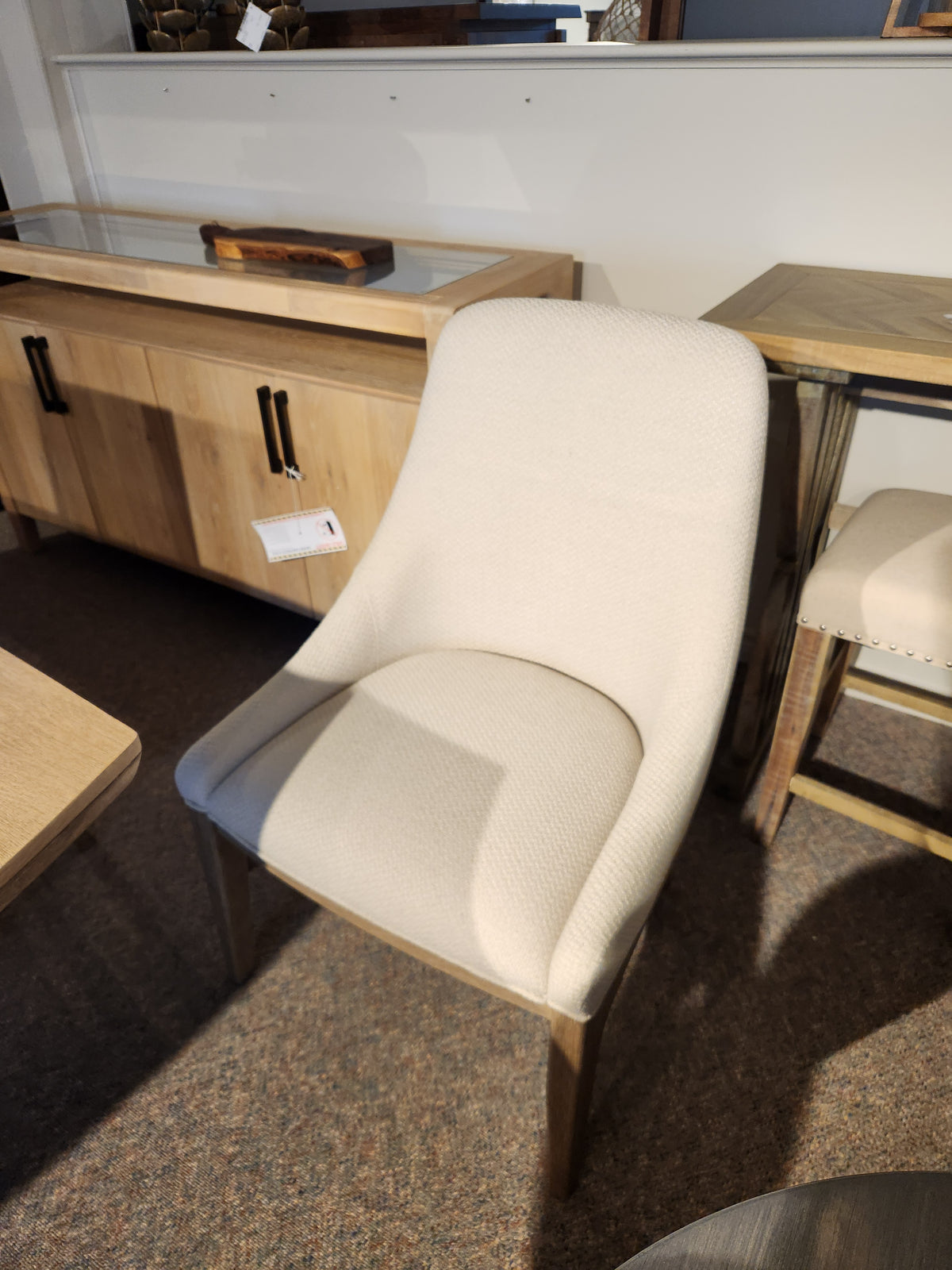 A beige upholstered chair with wooden legs pairs well with the Magnussen D5878 - Trestle 5 Piece Dining Package.