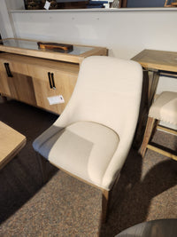 A beige upholstered chair with wooden legs pairs well with the Magnussen D5878 - Trestle 5 Piece Dining Package.