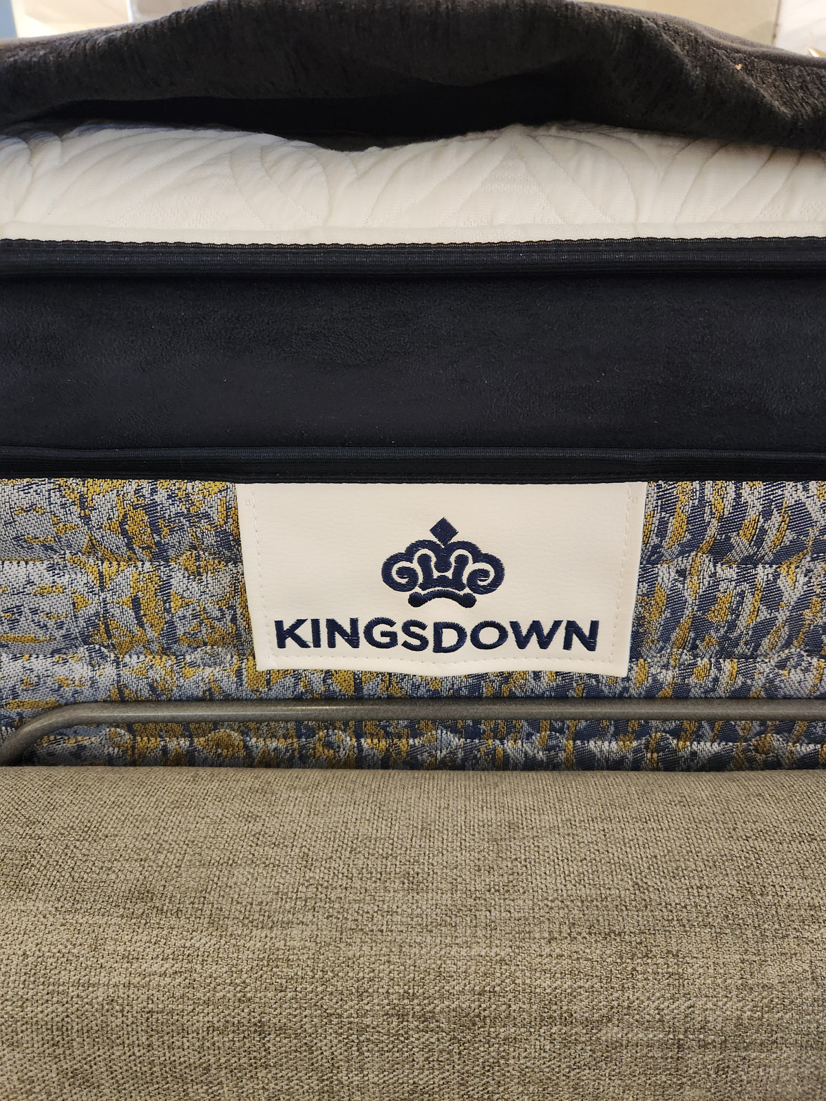 Close-up of a KingsDown Garland ET Plush Mattress label, showing micro gel tech and its patterned surface with bedding.