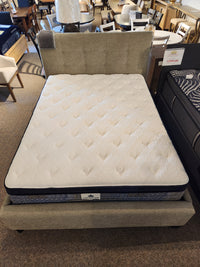 A KingsDown Garland ET Plush Mattress on display, paired with a beige upholstered bed frame for cooler sleep comfort.
