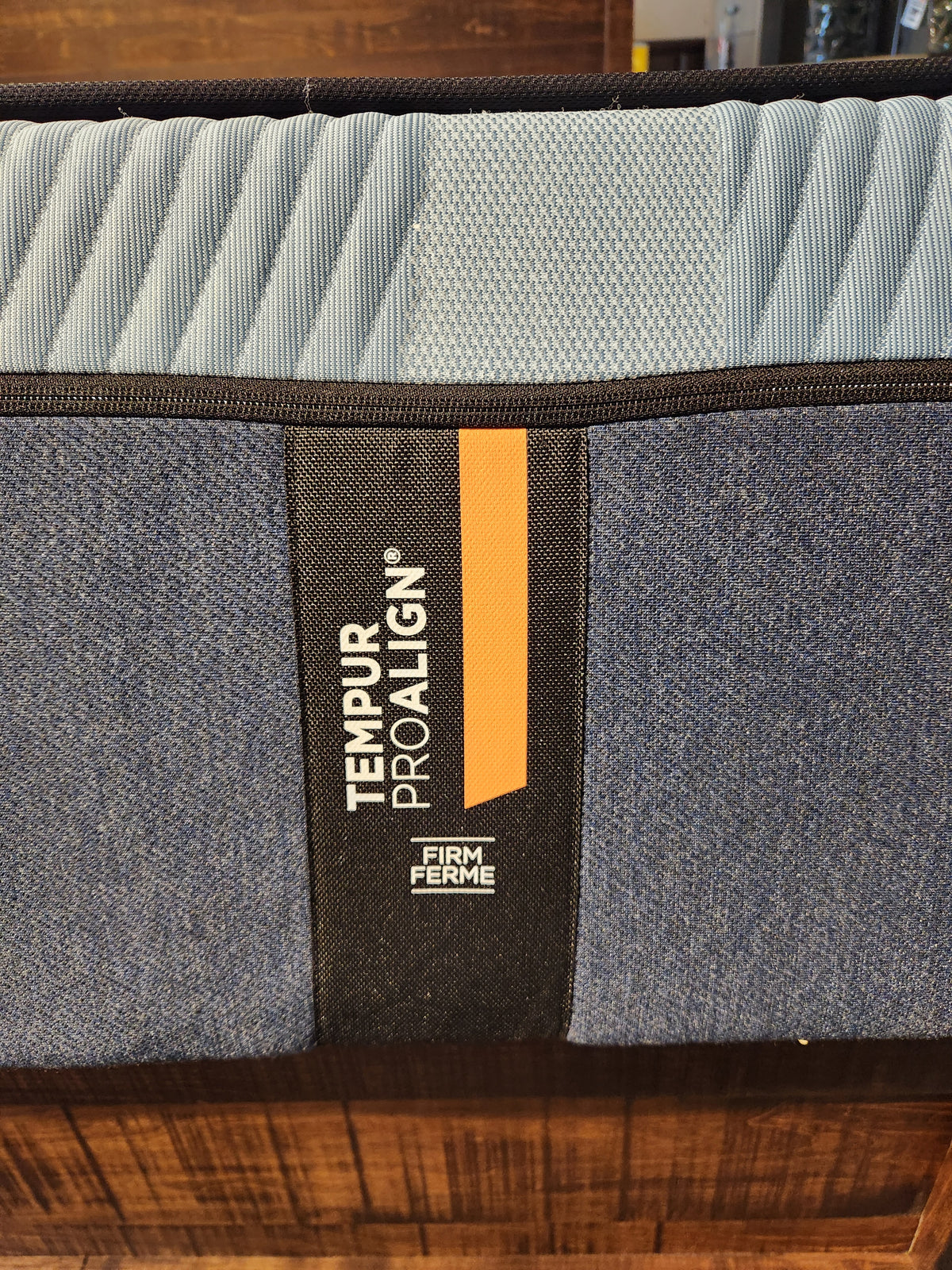 Close-up of a Tempur-pedic Pro Align 2.0 - Firm mattress label with blue fabric, known for pressure relief and bold branding.