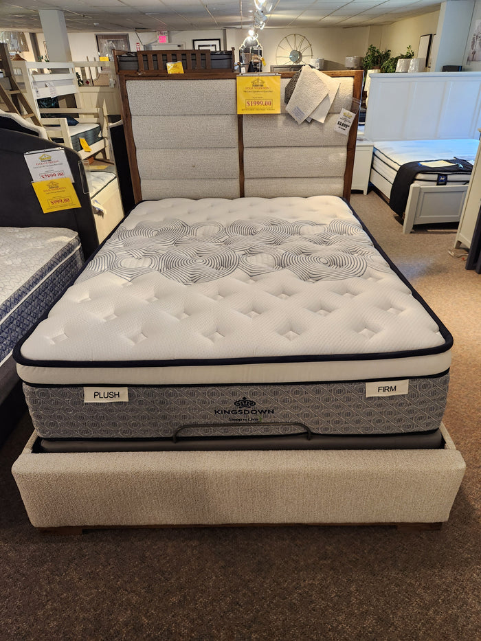 A KingsDown Radiance 2 ET Firm Mattress on a beige bed frame, labeled "Plush" and "Firm" in the showroom.