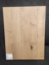 A display of Beckham Brothers’ Montana Plank White Oak flooring with visible grain, knots, and a label in the corner.