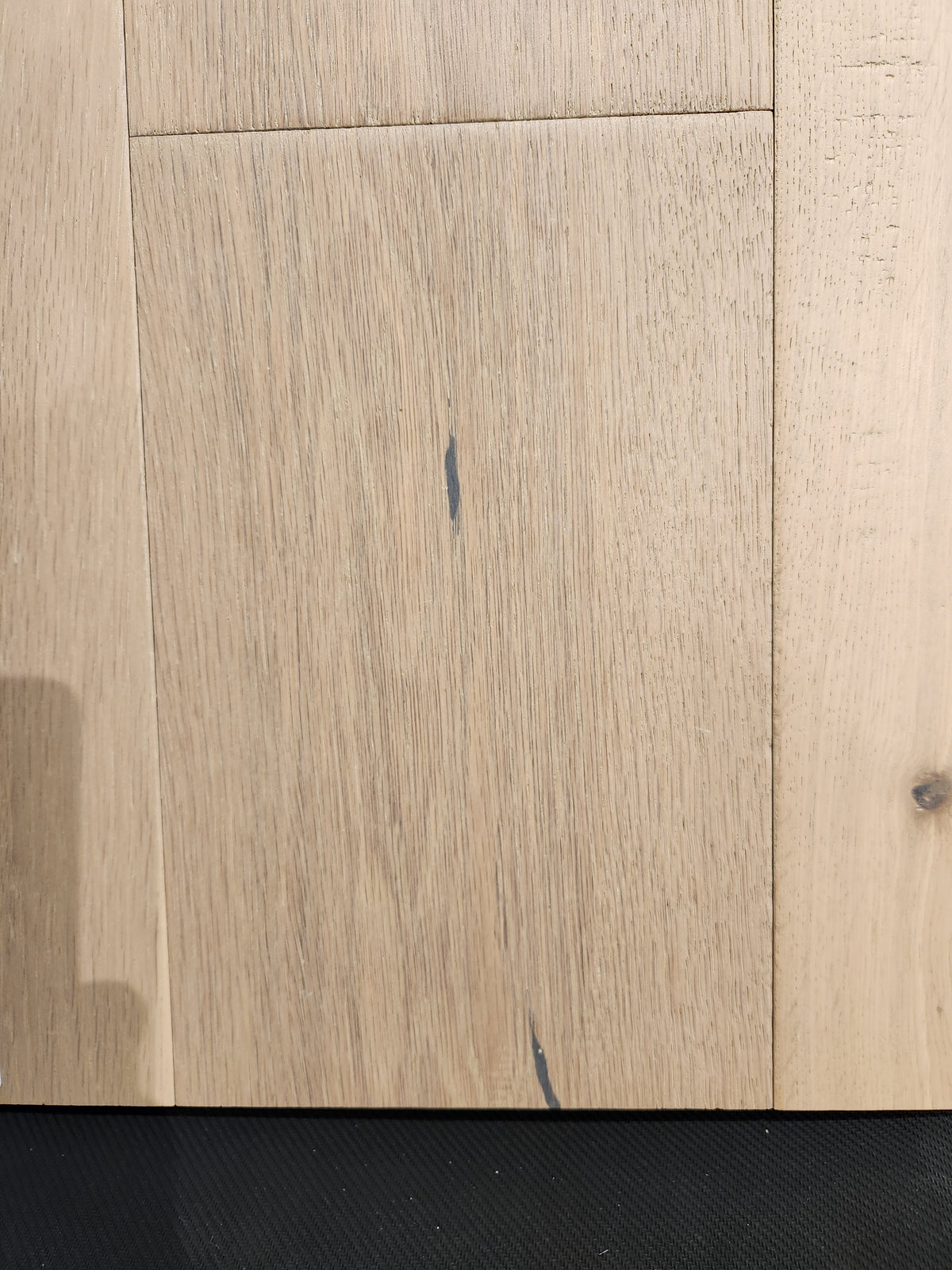 Montana Plank White Oak by Beckham Brothers: light premium hardwood with visible grain and dark streaks on black.