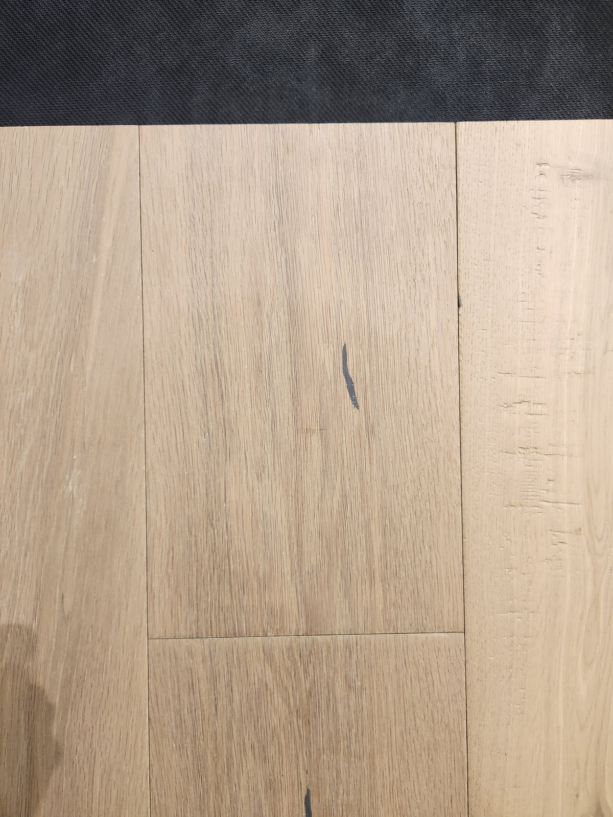Montana Plank White Oak by Beckham Brothers: light-toned oak flooring with grain, small dark marks, and a dark top edge.