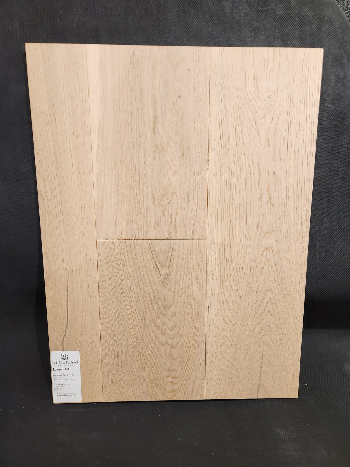 Beckham Brothers Montana Plank White Oak sample board with grain pattern, displayed upright on a dark background.