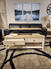 A transitional casual living room with a navy sofa, Magnussen T6310-Echo Isles table, and landscape wall art.