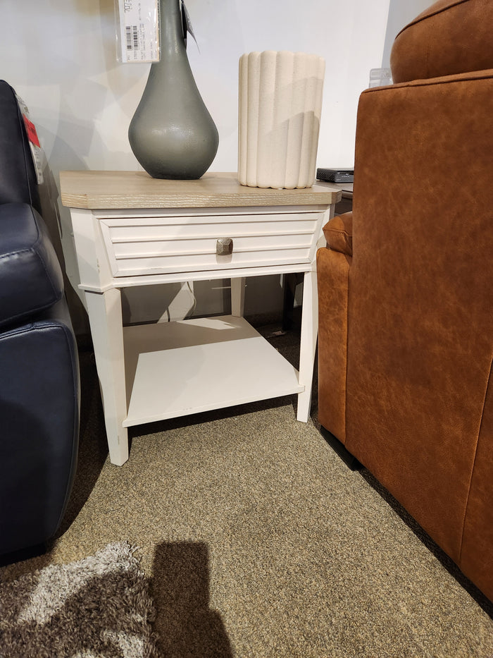 The Magnussen B6310-Echo Isles End Table with drawer and shelf sits between a blue sofa and a brown armchair.
