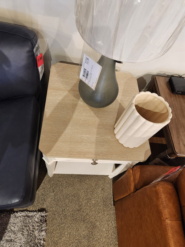 The Magnussen B6310-Echo Isles End Table sits between a sofa and brown armchair, topped with a lamp and ribbed vase.