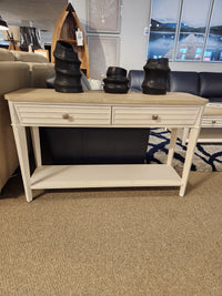 The Magnussen T6310-Echo Isles Sofa Table in white wood with oak top and 2 drawers, shown in a showroom.