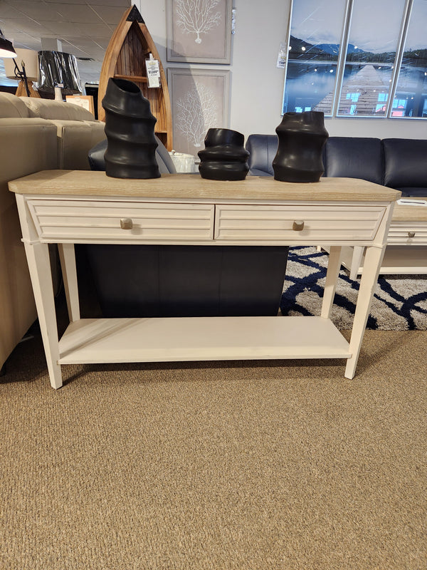 The Magnussen T6310-Echo Isles Sofa Table in white wood with oak top and 2 drawers, shown in a showroom.