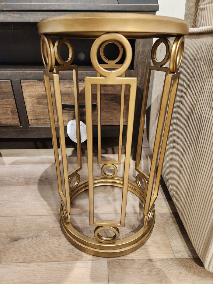 The Magnussen T6300 - Lorena Round Accent Table with brass finish sits by a beige sofa in a traditional room.