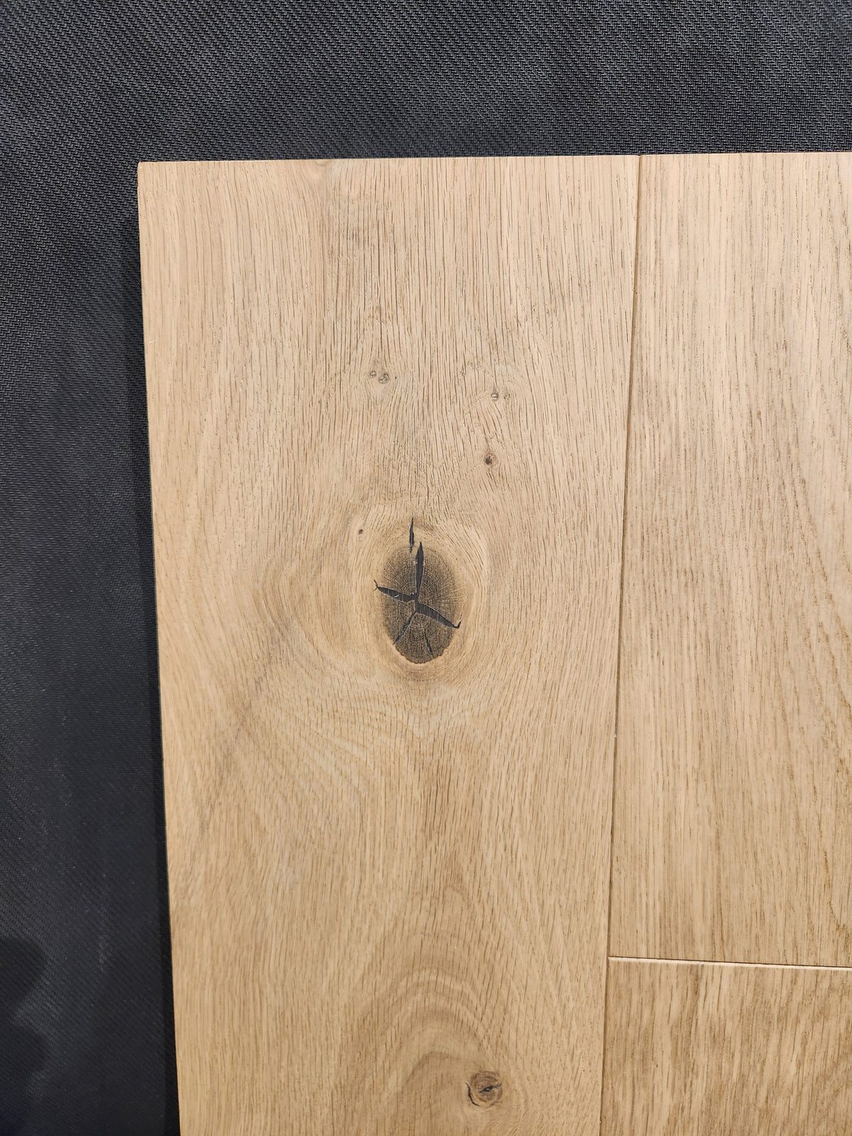 Beckham Brothers’ New York Loft White Oak-Hardwood panel with a dark knot on a textured background.