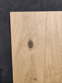 Beckham Brothers’ New York Loft White Oak-Hardwood panel with a dark knot on a textured background.